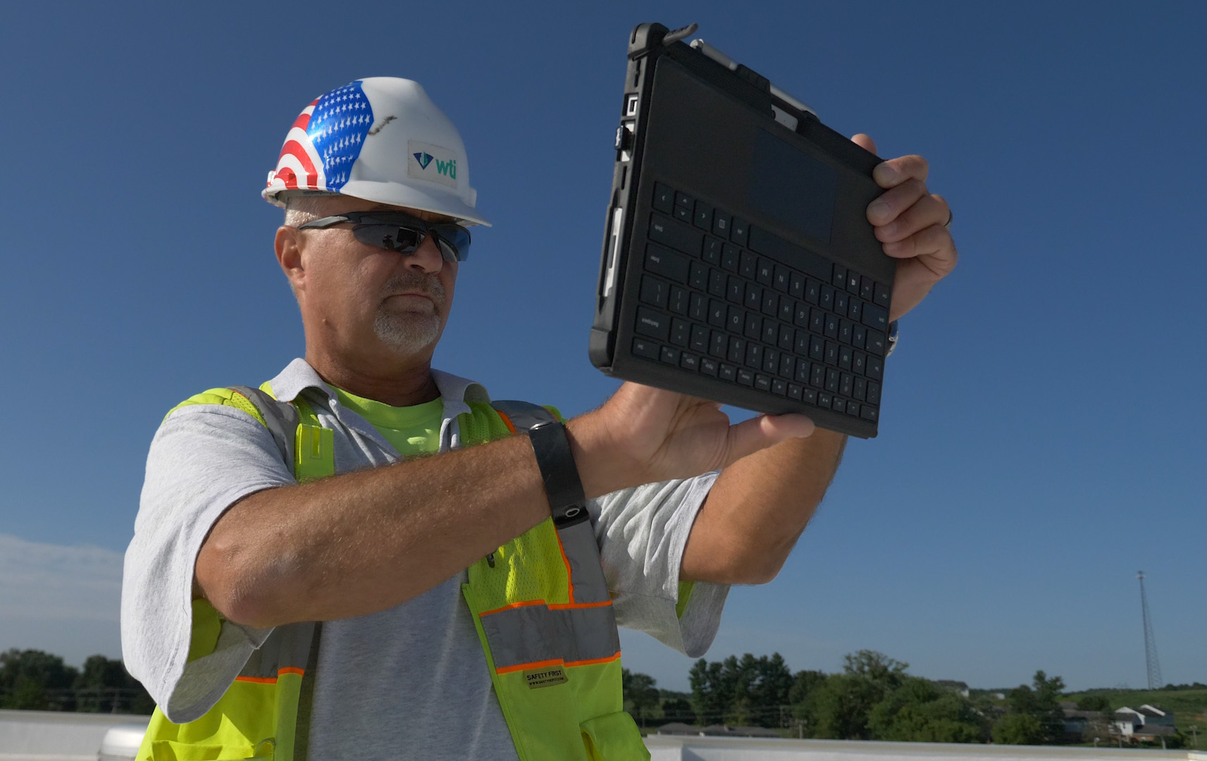 Roofer inspecting roof on a tablet.