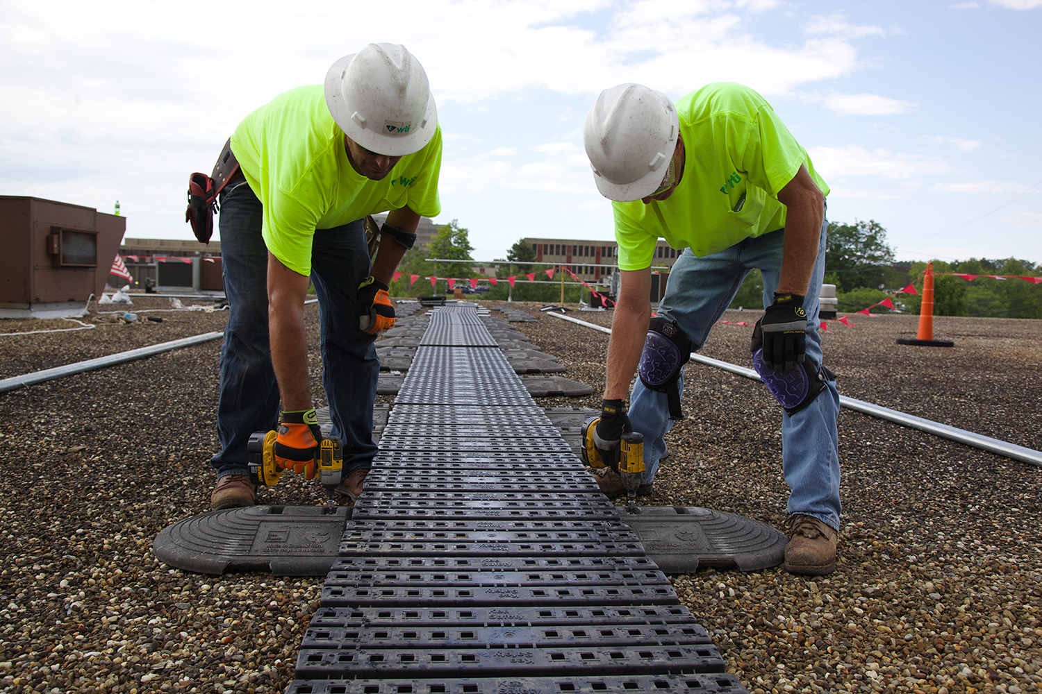 Roofers installing walkways on roof.