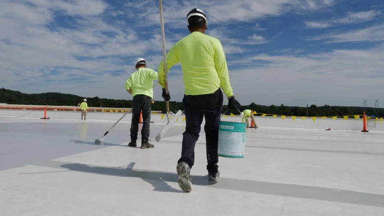 Construction workers on rooftop with roofing materials