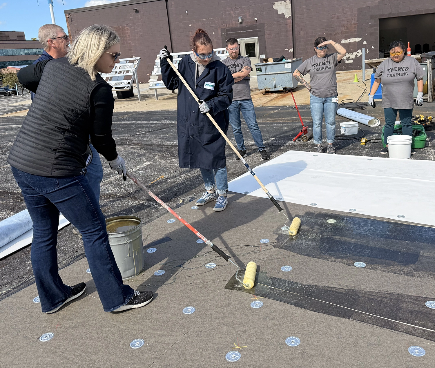 Two women applying a roof coating in a training.